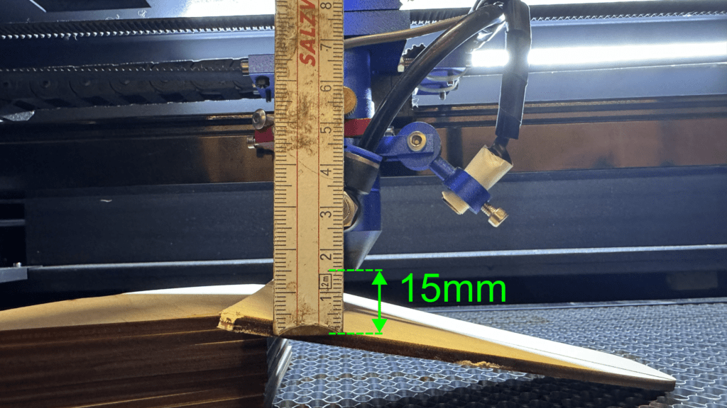 Laser head positioned over the narrowest part of the engraved line, with a ruler measuring the focal distance at 15mm.

