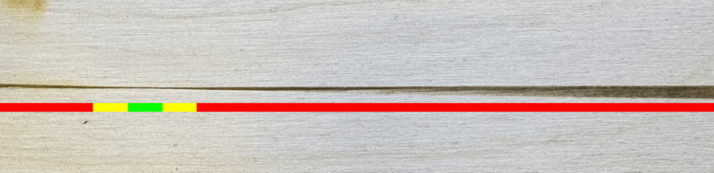 Adjusting laser focus using a line engraving analysis on wood. The line transitions from wide to narrow and back, with red, yellow, and green zones highlighting the focus point.